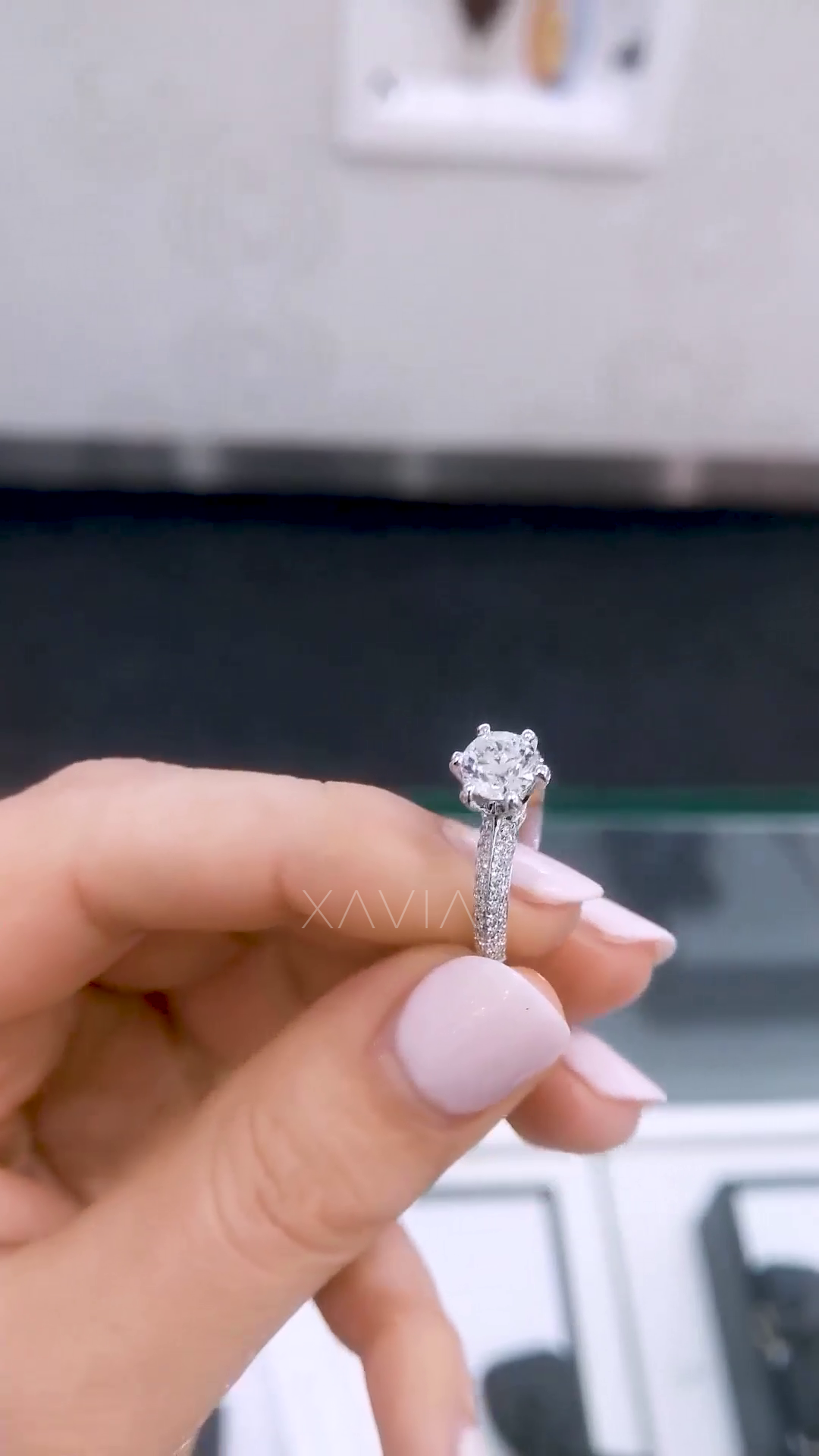 Angled view of round diamond solitaire engagement ring with pavé split shank and handcrafted white gold setting